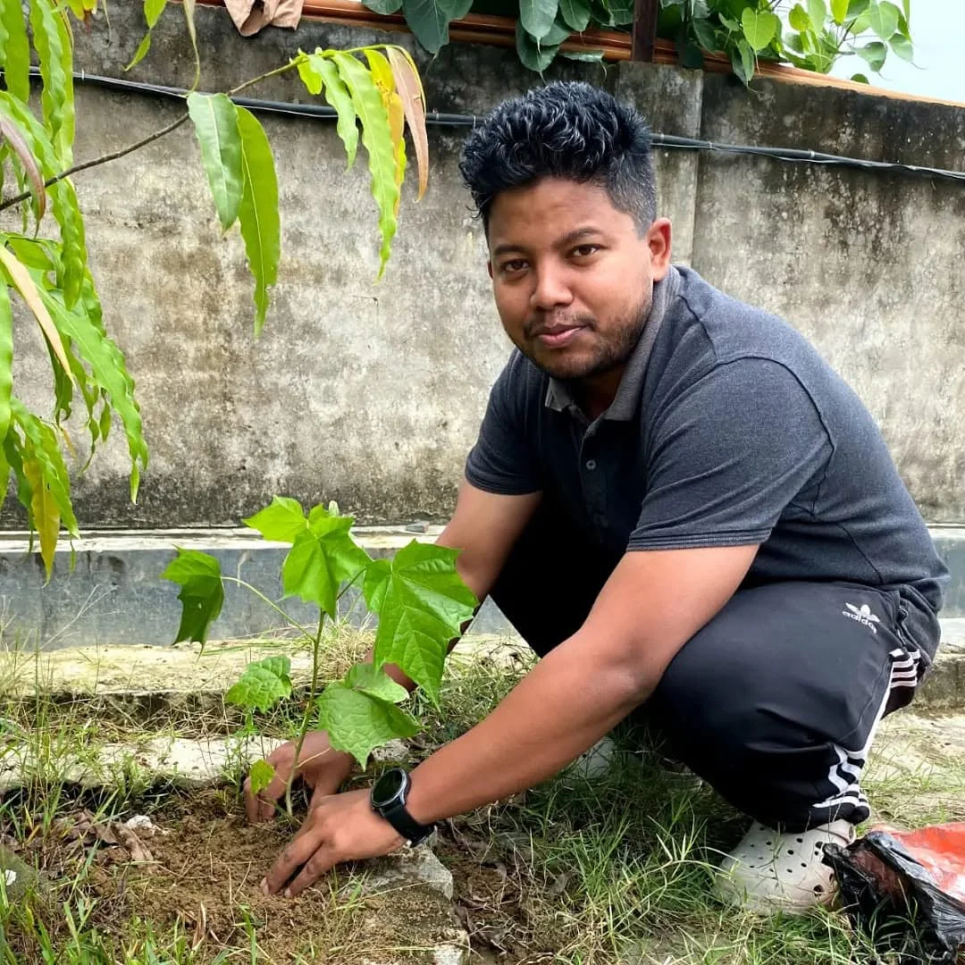 A volunteer planting a sapling during a tree plantation drive